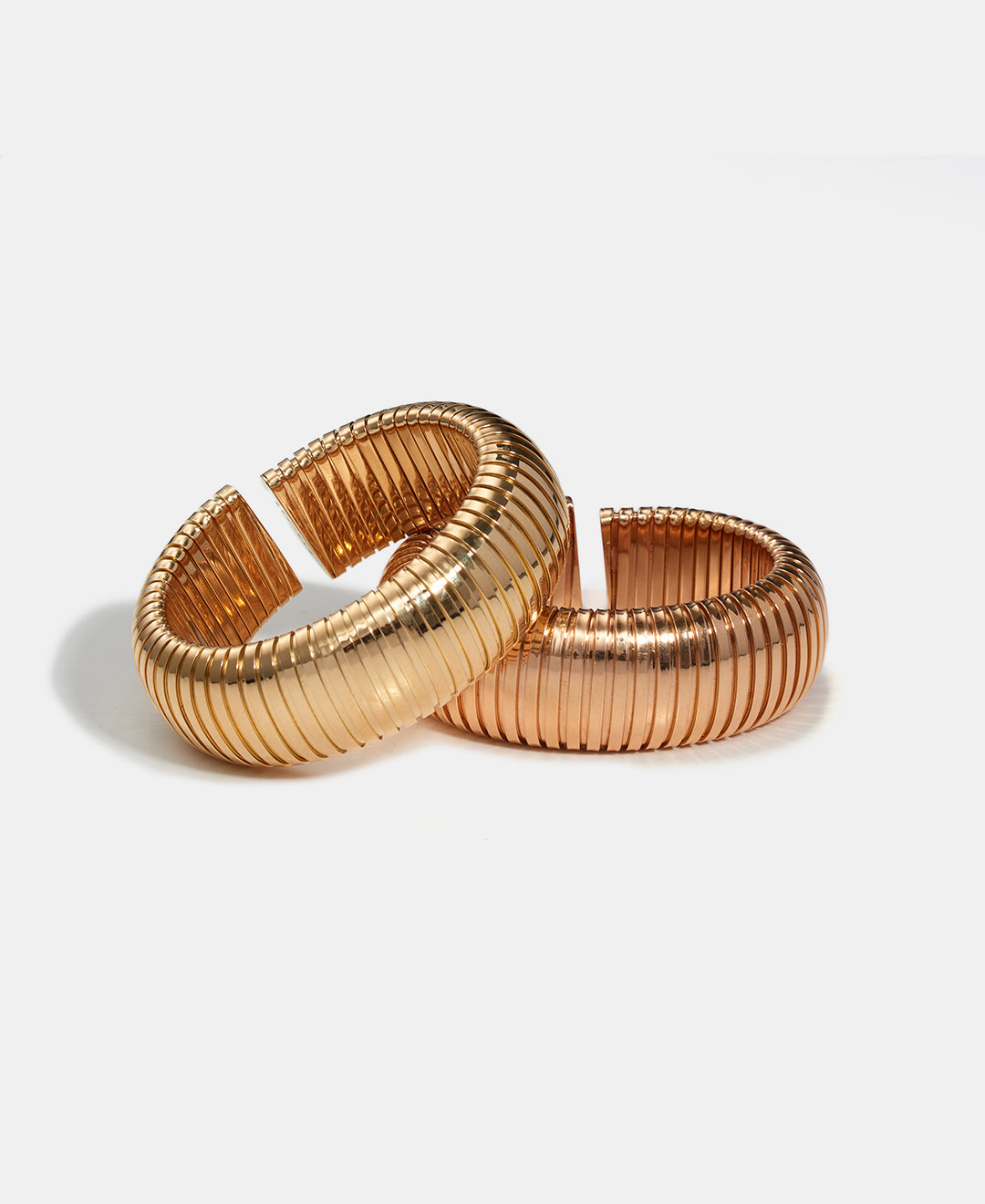 Two domed cuffs, one in yellow gold, and one in rose gold are displayed on a white background.