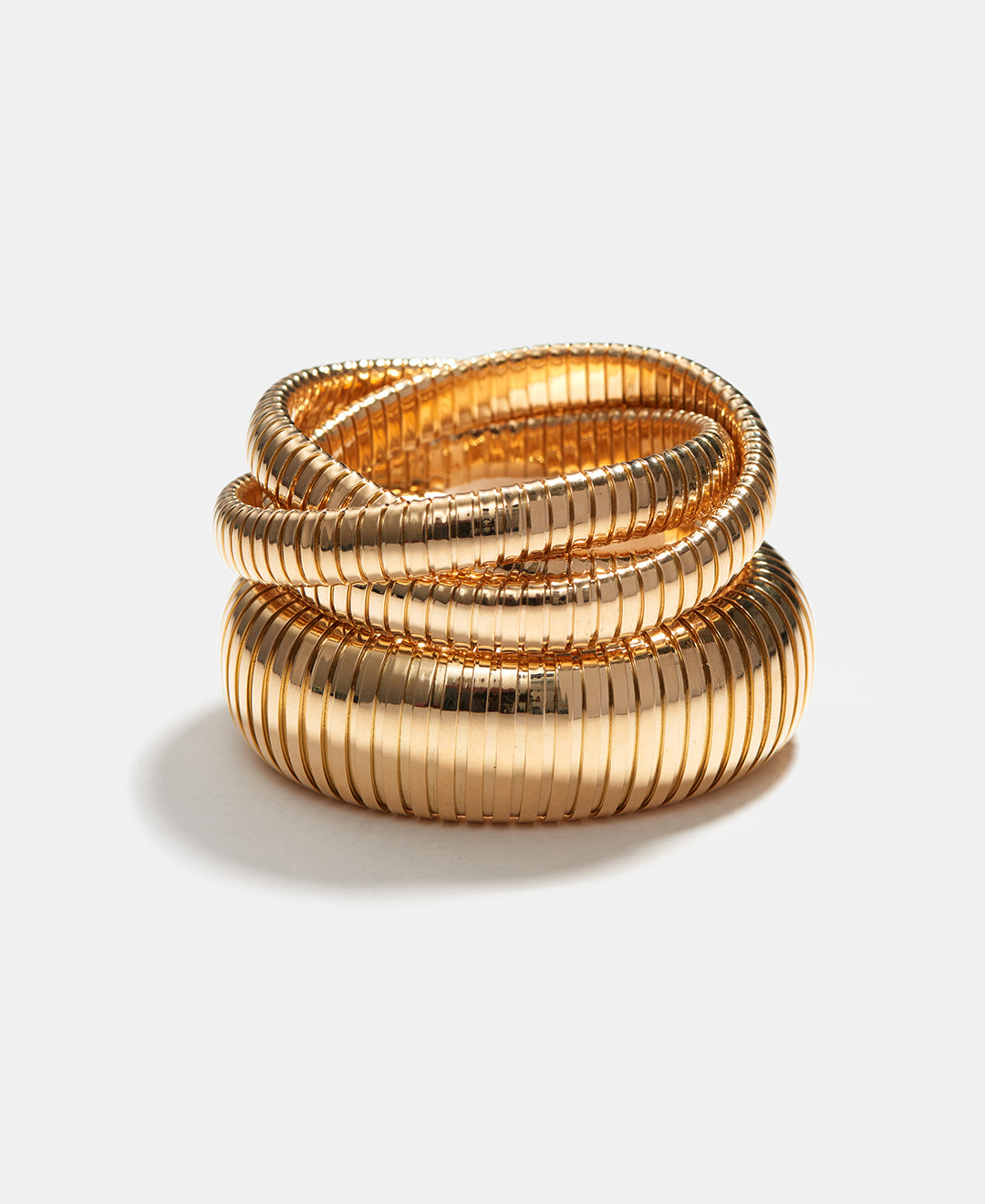 A yellow gold Rolling Bracelet stacked on top of a yellow gold Domed Cuff on a white background.