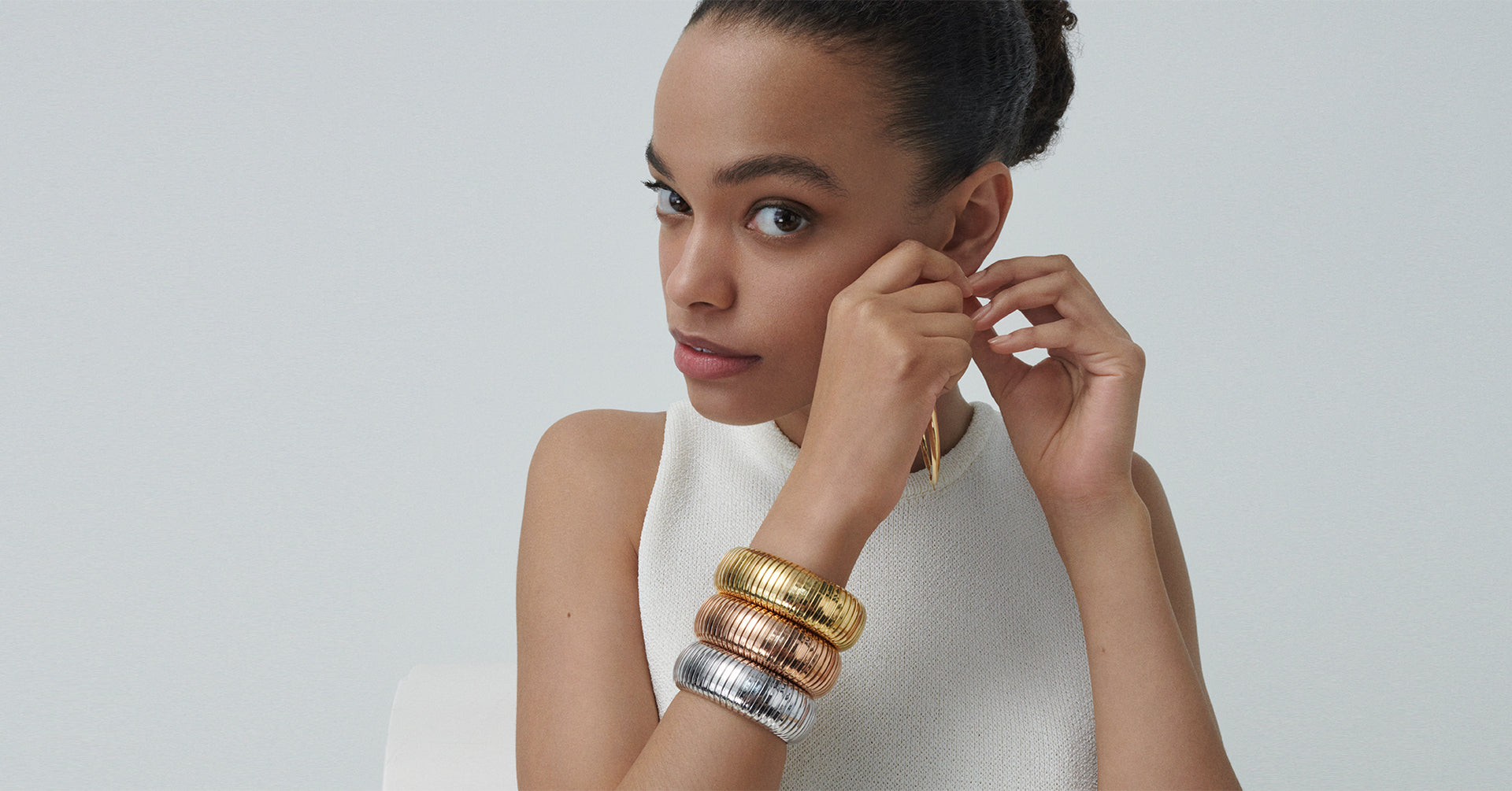 A model is wearing three domed cuff stacked (Yellow gold, Rose gold, and White gold)