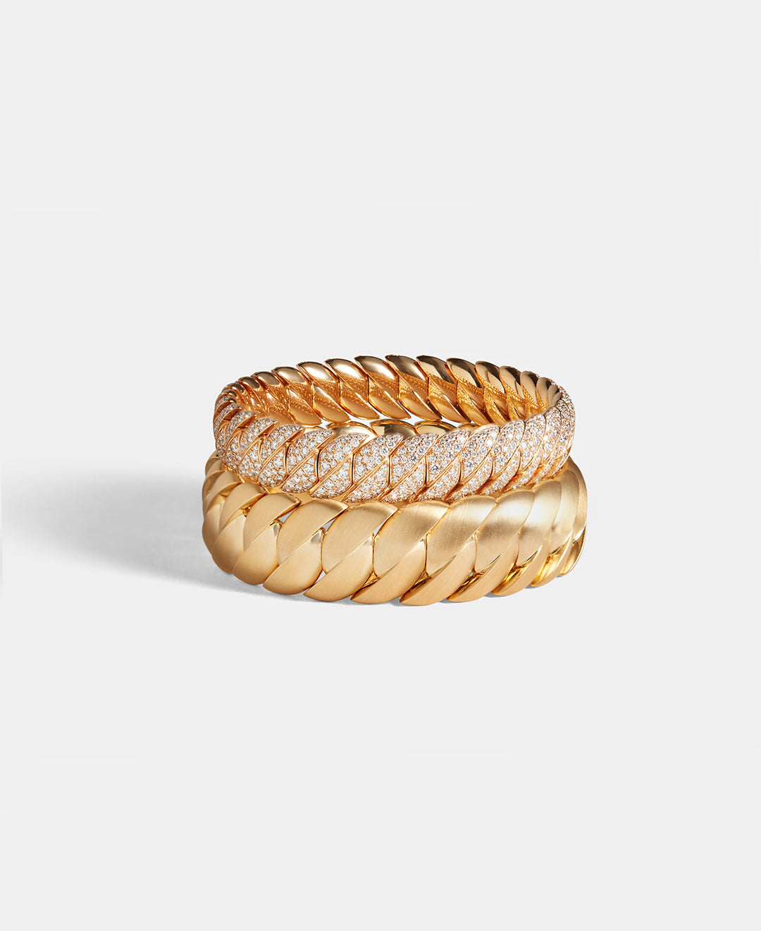 Two wave bracelets, one in yellow gold, and one in yellow gold with diamonds are displayed on a white background.